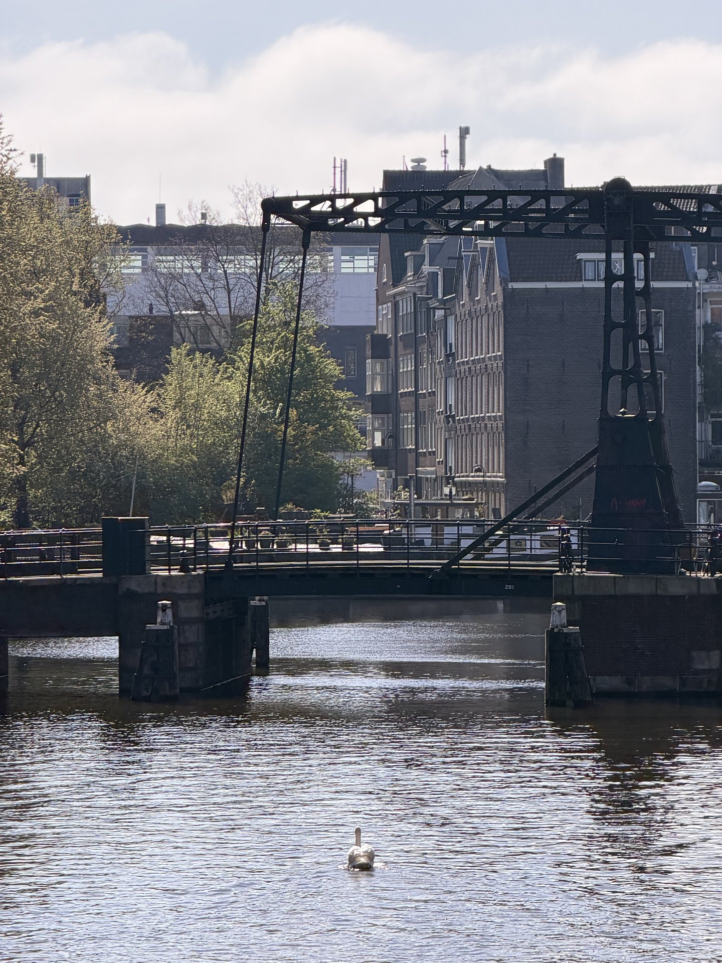 This serene photo captures the Montelbaansbrug in Centrum, Amsterdam, with its distinctive drawbridge structure spanning a calm canal